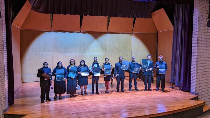 Image of young men and women dressed in concert attire displaying honors certificate.