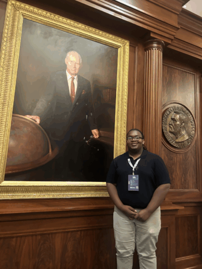 Samuel Brown standing next to a life-sized painting of Dr. Norman E. Borlaug      