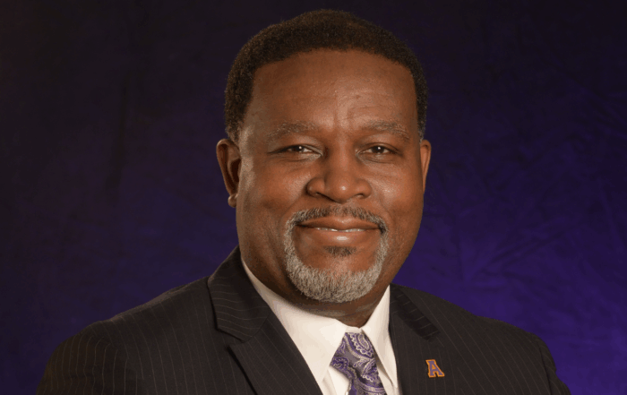 Dr. Tracy M. Cook, president of Alcorn State University, in professional headshot wearing dark suit and purple patterned tie with Alcorn lapel pin