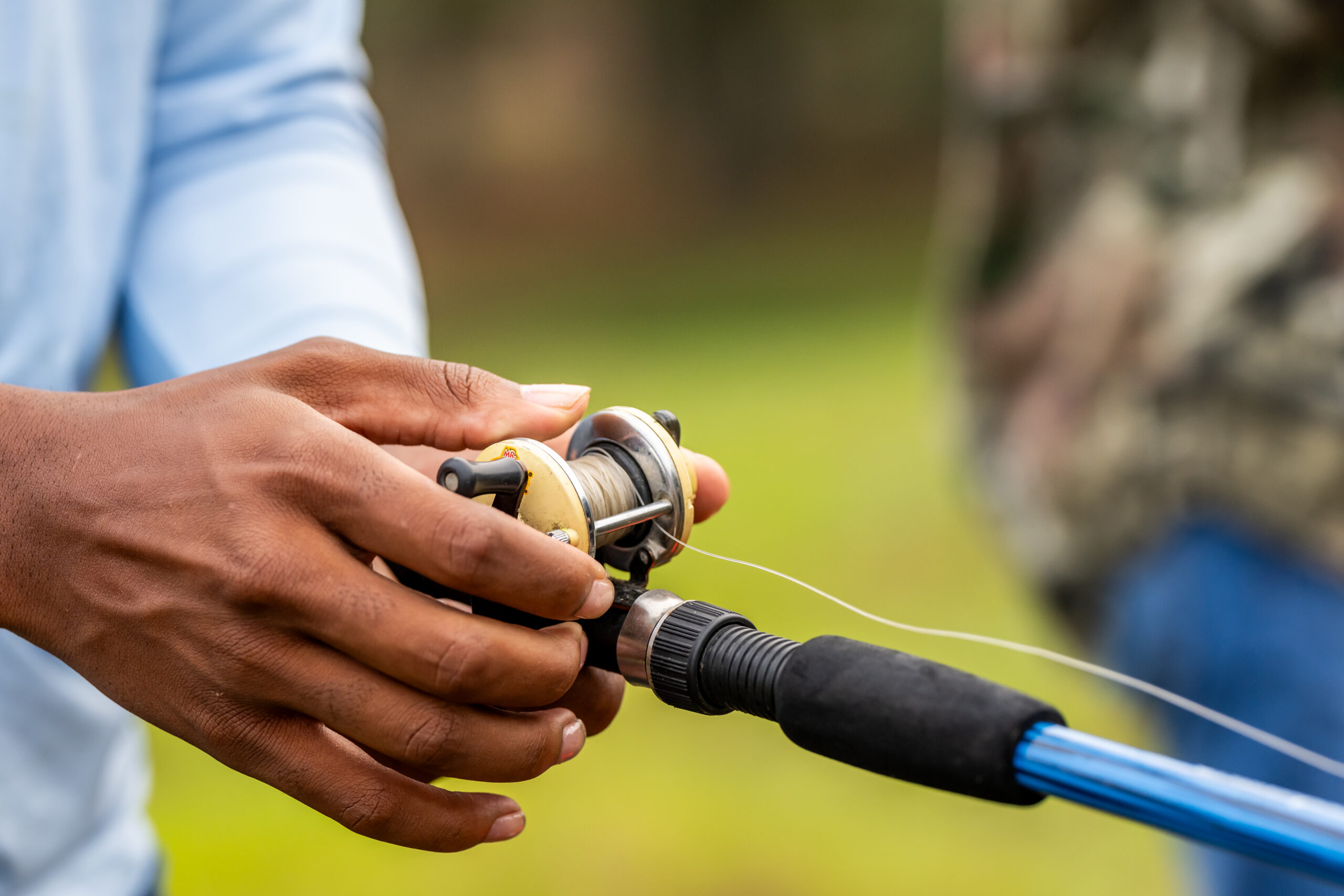 Close up photo of student holding a fishing reel.