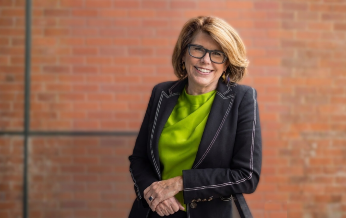 Professional headshot of Dr. Julie Taylor in dark suit and a green shirt.