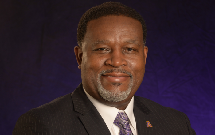 Dr. Tracy M. Cook, president of Alcorn State University, poses for a professional headshot wearing a pinstripe suit and purple paisley tie.