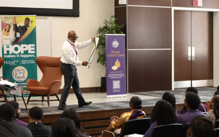 Michael Harper on stage dressed in white button down and black dress pants presenting MyCareerCloset