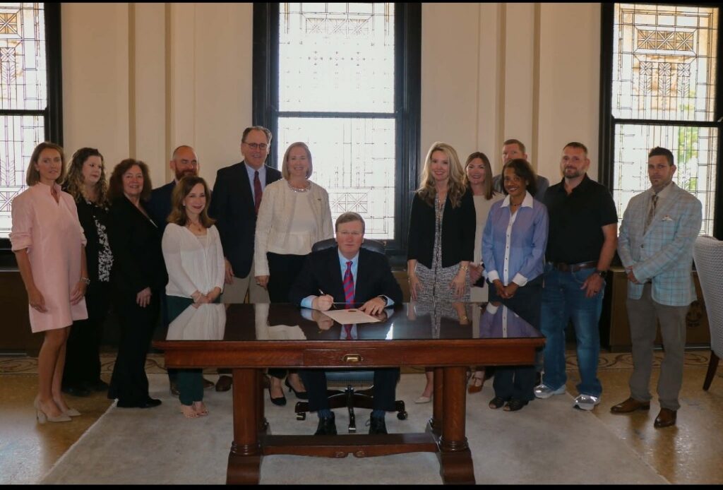 Alcorn State University student John White, second from right, stands with Mississippi Governor Tate Reeves and fellow advocates as Governor Reeves signs the Overdose Awareness Bill in a formal state government office.