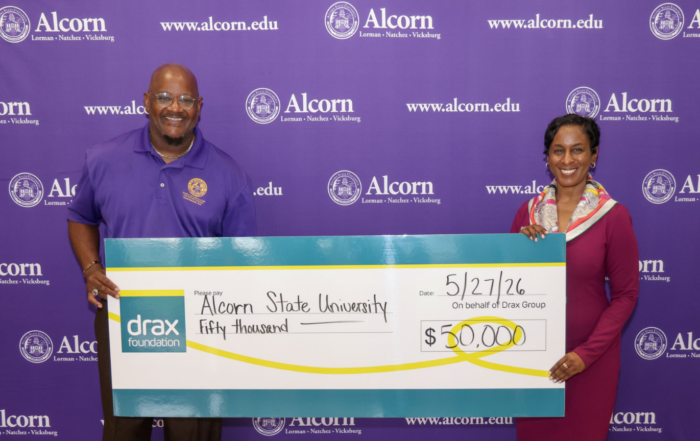 Dr. Dexter Wakefield of Alcorn State and Deidra Jackson of Drax hold a $50,000 Drax Foundation check in front of an Alcorn State University backdrop.