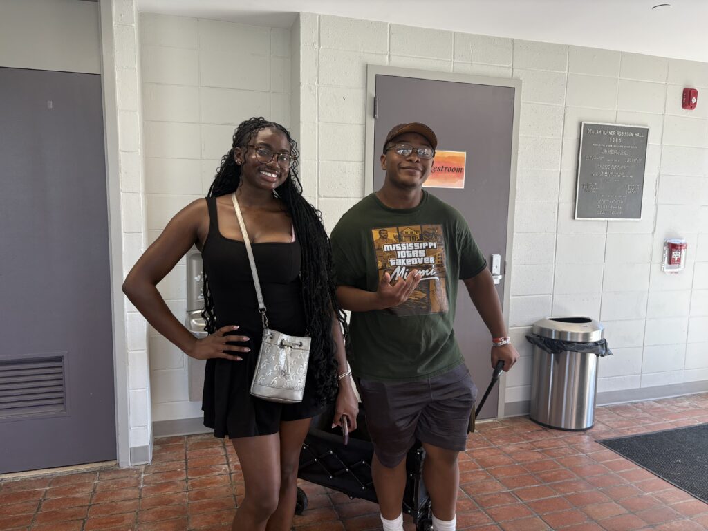 Imani Jones stands with Carmello Miles, who holds the handle of a folding wagon, near a water fountain in the lobby on Move-In Day.