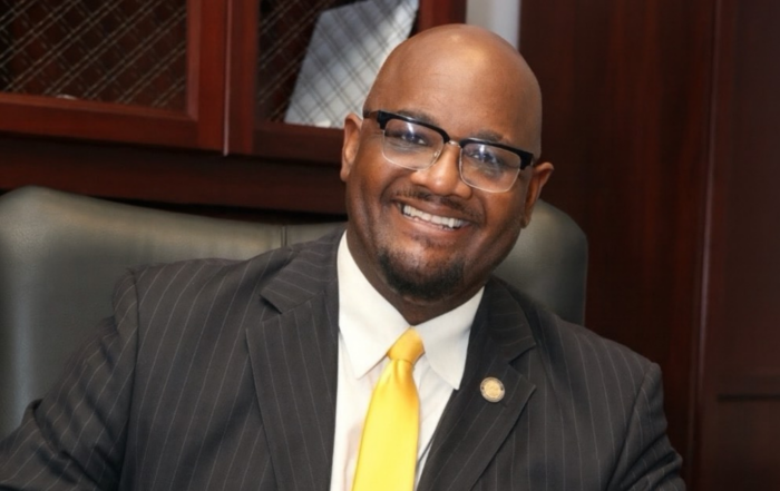 Dr. Dexter B. Wakefield I, Dean of Alcorn State University's College of Agriculture and Applied Sciences, smiling in a pinstripe suit and gold tie, seated in an office.